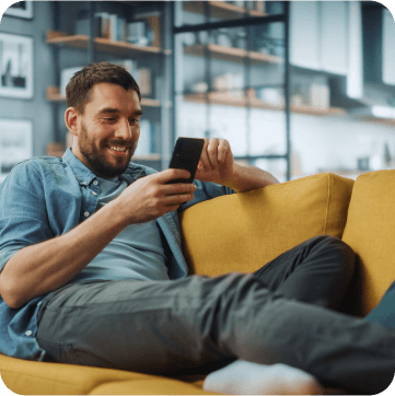 Man relaxing while scrolling on his phone on yellow couch.