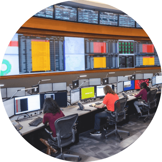 Tech team members working at computers with many screens in the background