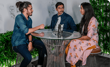 Three individuals sitting around a table, chatting