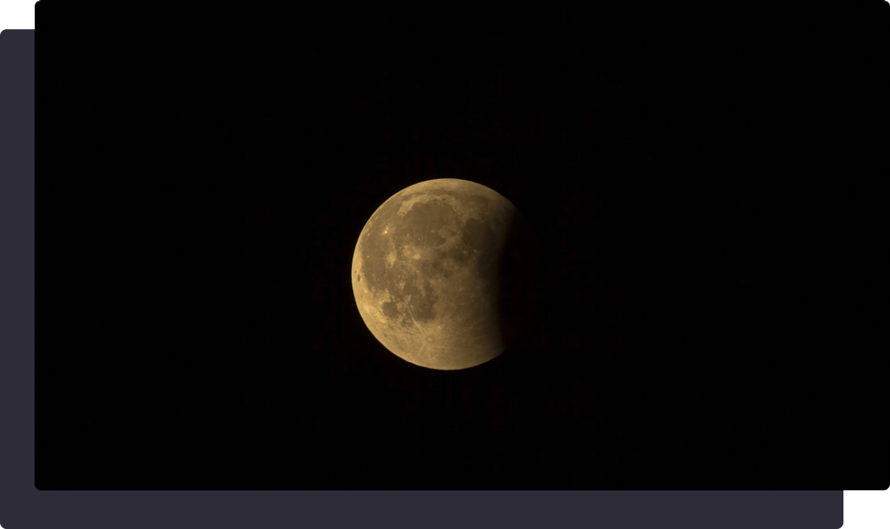 A partial lunar eclipse with a dark shadow covering part of the moon.